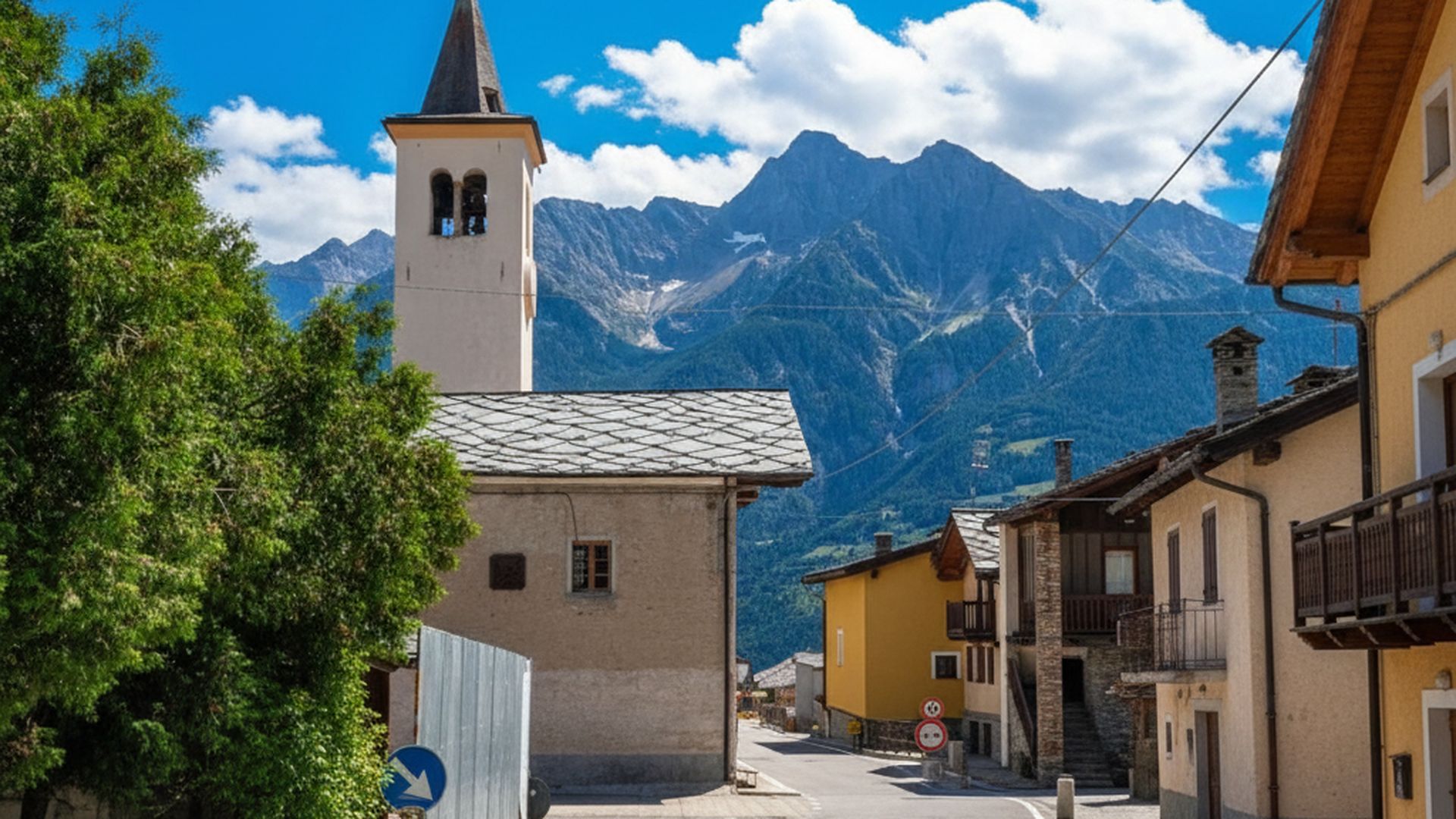 Borgo alpino con campanile e montagne in Valle d'Aosta